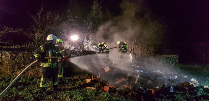 Feuerwehr löscht brennenden Holzhaufen in Scheie